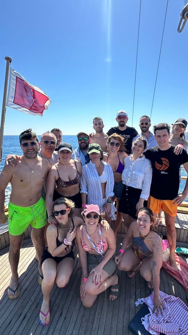 Un gruppo WeRoad in viaggio posa insieme per una foto sul ponte di legno di una barca, con il mare aperto alle spalle.