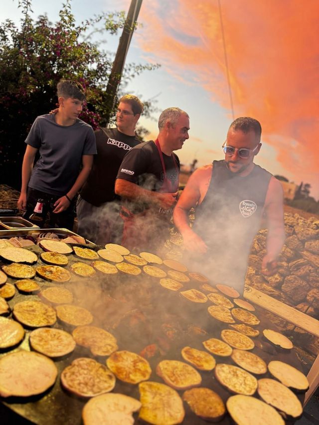 Viaggio di gruppo WeRoad: uomini che cucinano verdure alla griglia all'aperto al tramonto.