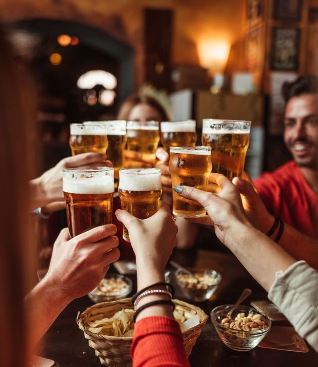 A WeRoad group trip toasting with glasses of beer in a dimly lit pub.