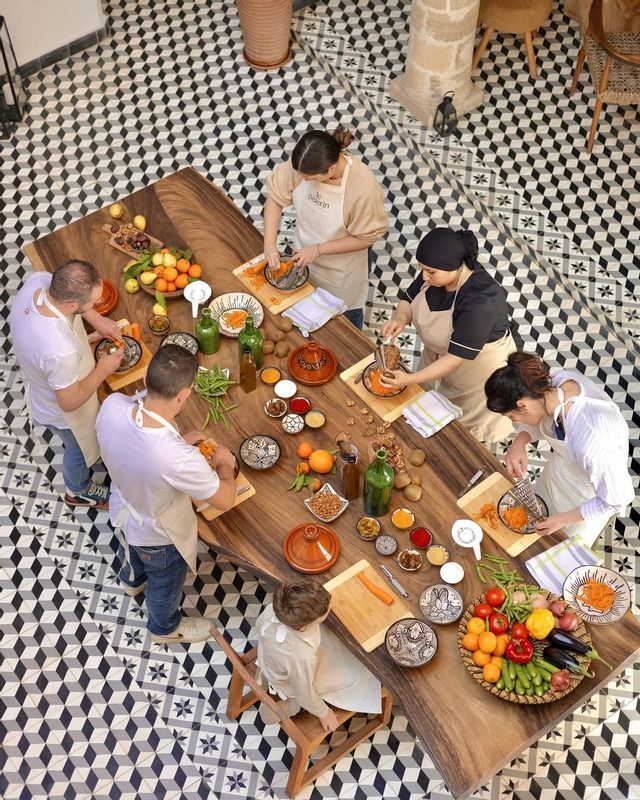 An overhead view of a WeRoad group trip participating in a cooking class, preparing fresh vegetables on a large wooden table.