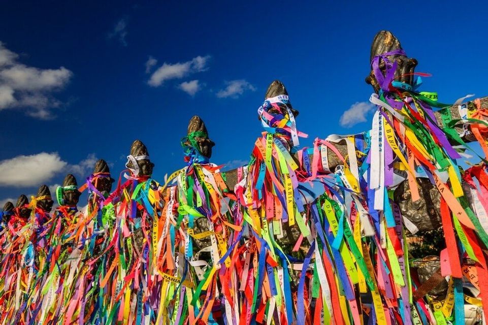 Une vue en contre-plongée de nombreux rubans colorés attachés à des poteaux de clôture sur un ciel bleu vif avec quelques nuages.