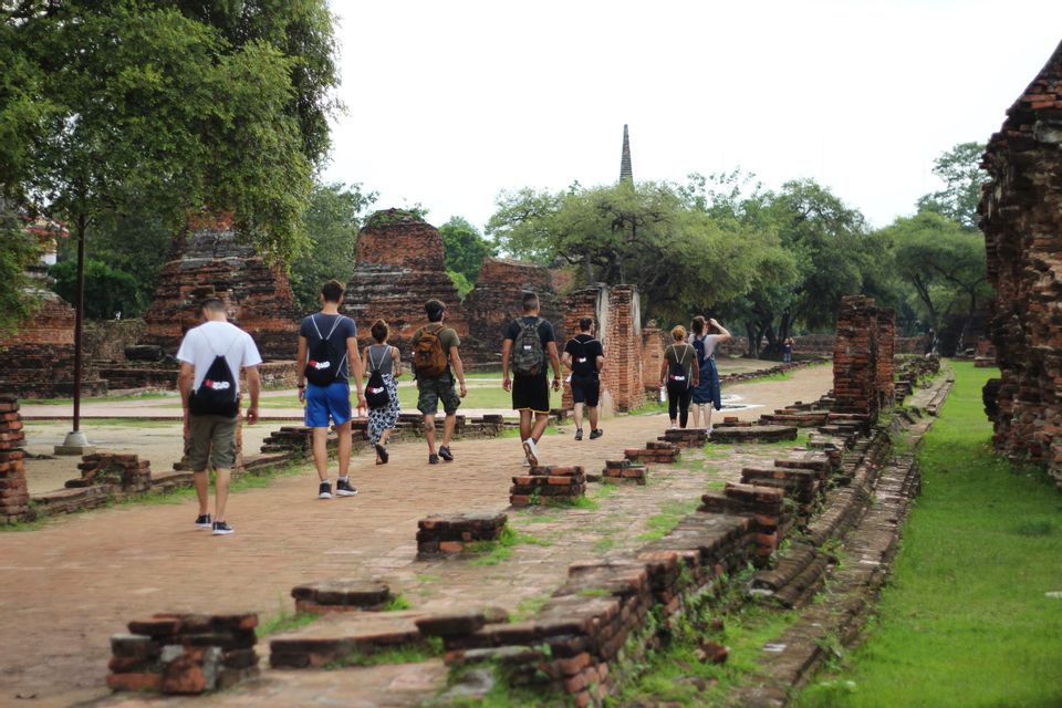 Un voyage de groupe WeRoad se promène le long d'un chemin de briques entouré d'anciennes ruines de temples et d'arbres verts.