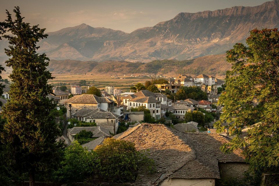 Vue plongeante sur un village de maisons en pierre aux toits de tuiles, niché dans une vallée au pied d'une montagne.