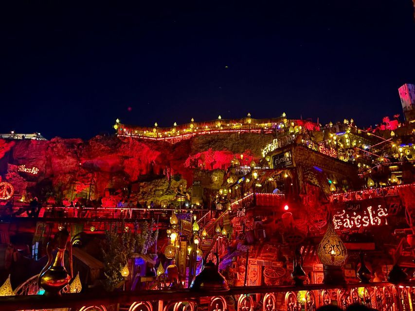Una location all'aperto su più livelli, ricavata in una parete rocciosa, illuminata di notte da centinaia di lampade e lanterne dai toni caldi.