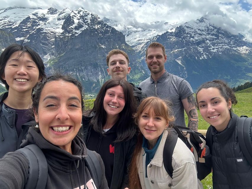 Un groupe WeRoad prend un selfie souriant avec une chaîne de montagnes enneigée en arrière-plan.