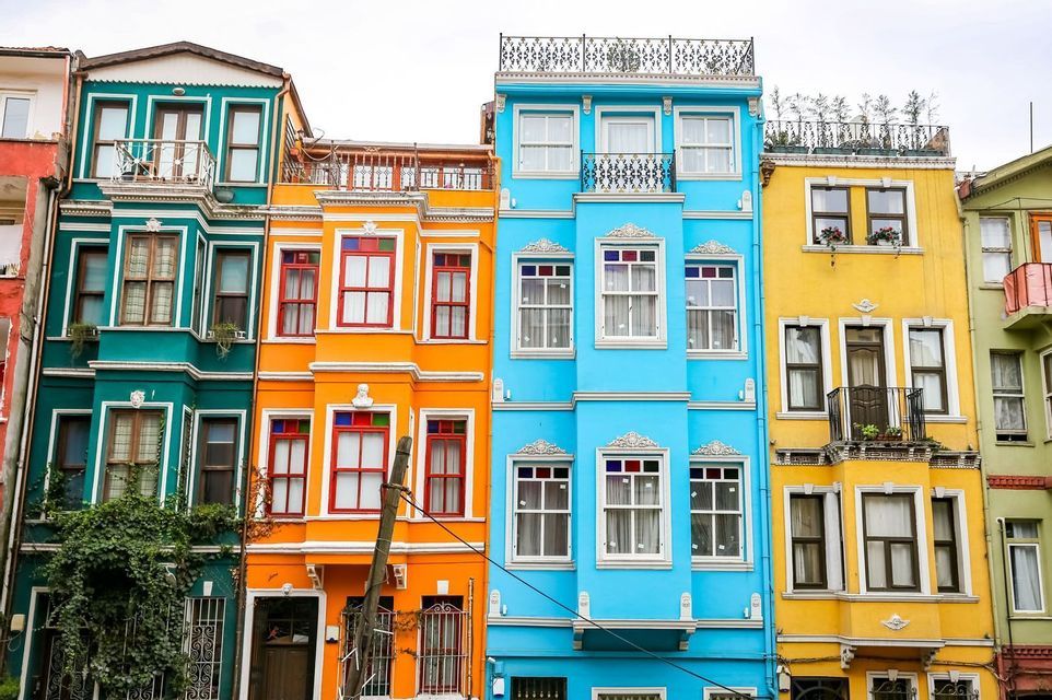 Facades of narrow, traditional houses painted in bright colors like blue, yellow, orange, and teal.