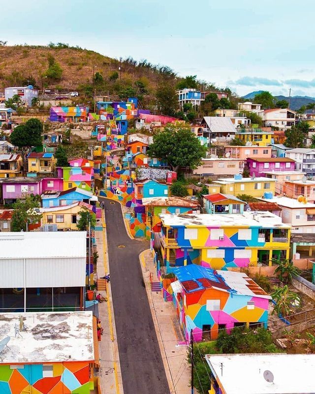 Una vista aerea di una città collinare con case e scale dipinte con vivaci motivi geometrici multicolori.