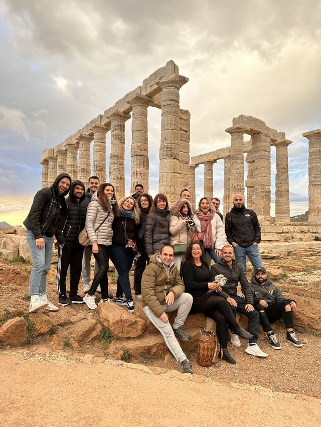Un viaggio di gruppo WeRoad in posa per una foto su una collina rocciosa con antiche rovine di templi sullo sfondo.