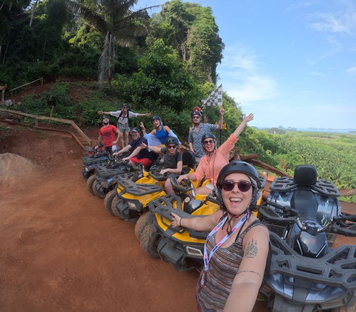 Eine WeRoad-Gruppe mit Helmen posiert für ein Selfie auf gelben Quads, die auf einem Feldweg mit Blick auf einen Dschungel geparkt sind.