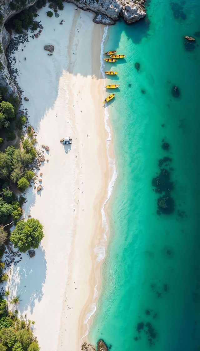 Una vista aerea dall'alto di kayak gialli allineati su una spiaggia di sabbia bianca accanto a un'acqua limpida e turchese.