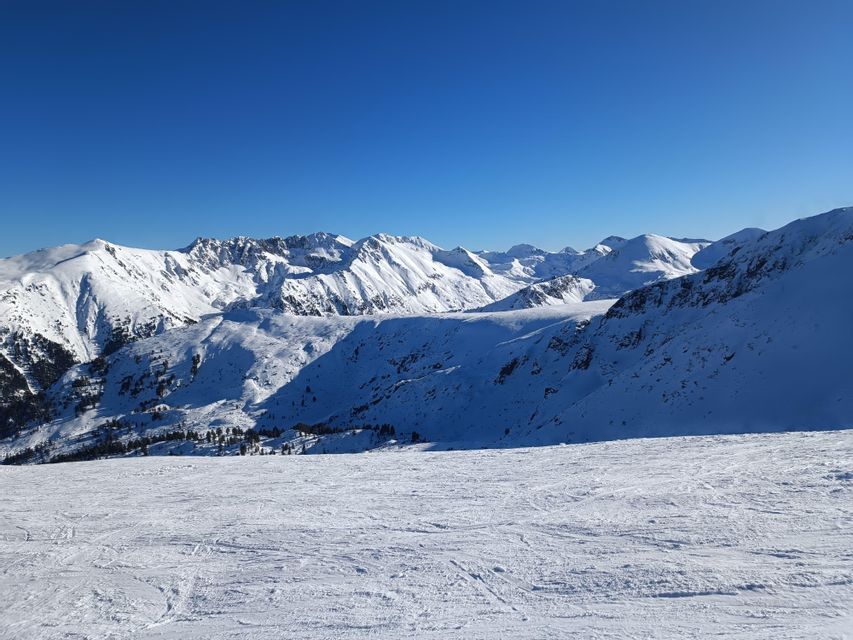 Une vaste chaîne de montagnes entièrement couverte de neige se dresse sous un ciel d'un bleu profond et sans nuages.