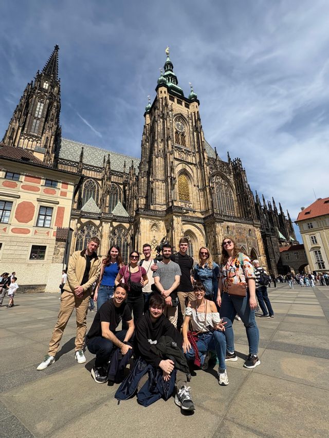 Eine WeRoad-Gruppe posiert für ein Foto auf einem sonnigen Platz vor einer prunkvollen gotischen Kathedrale.