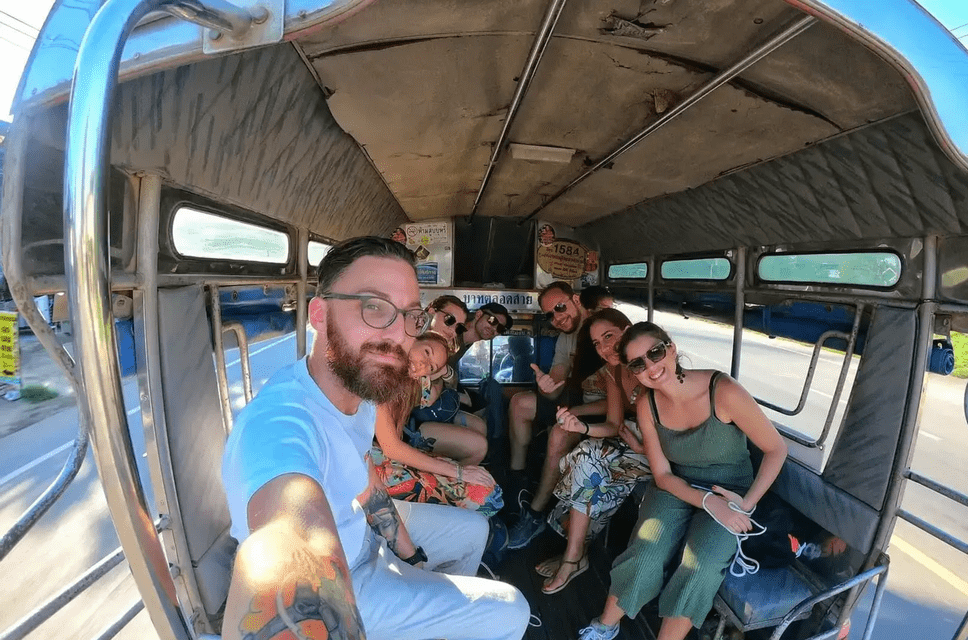 A WeRoad group trip smiles for a selfie while riding together in the back of an open-air vehicle.