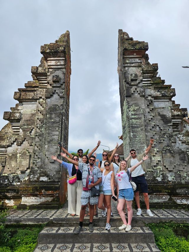 Un groupe WeRoad en voyage pose pour une photo sur des marches, entre deux grandes portes traditionnelles en pierre sculptée.