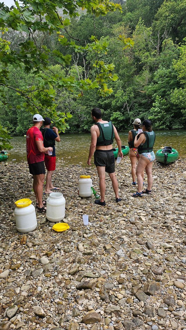 Un grupo de WeRoad, luciendo chalecos salvavidas, hace una pausa en una ribera rocosa con kayaks inflables.