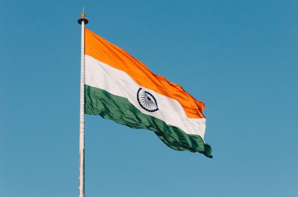 La bandiera tricolore dell'India sventola su un pennone contro un cielo azzurro e limpido.