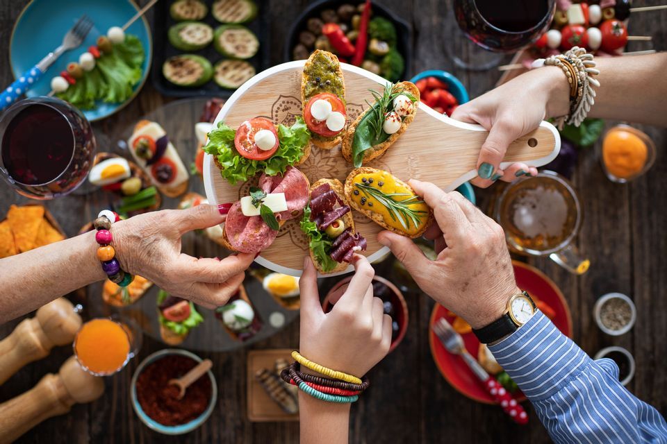 A top-down view of a WeRoad group trip sharing a platter of assorted bruschetta over a rustic table with other appetizers.