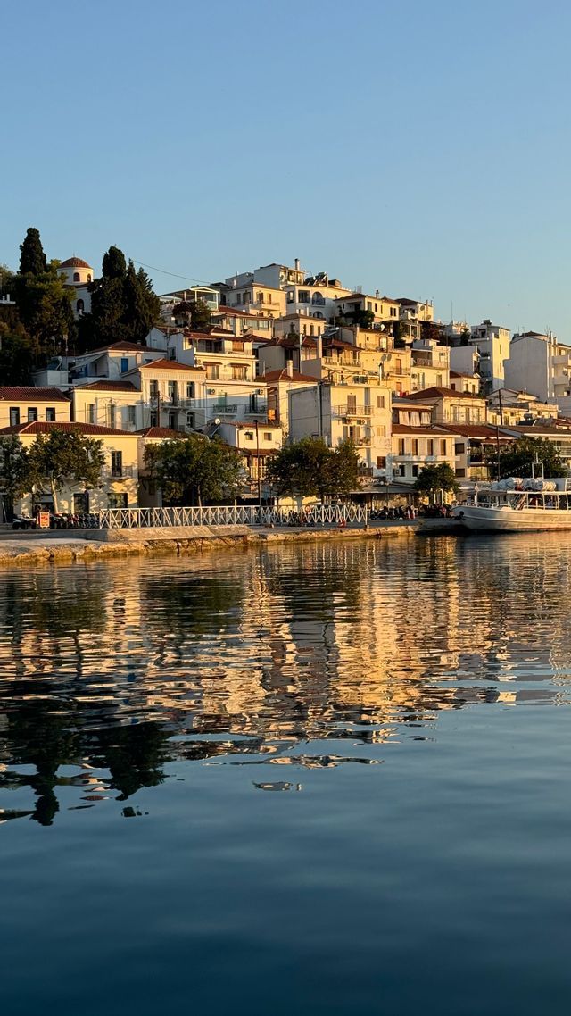 Edifici bianchi di una città costiera costruita su una collina si riflettono nell'acqua durante l'ora d'oro.