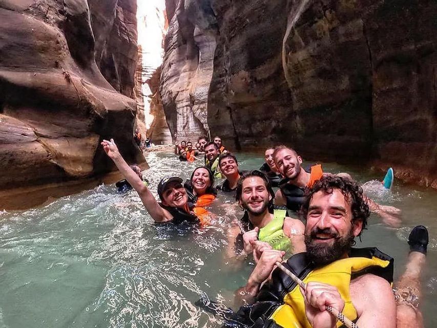 WeRoad Gruppenreise: Lächelnde Teilnehmer in Schwimmwesten schwimmen durch eine enge Schlucht.