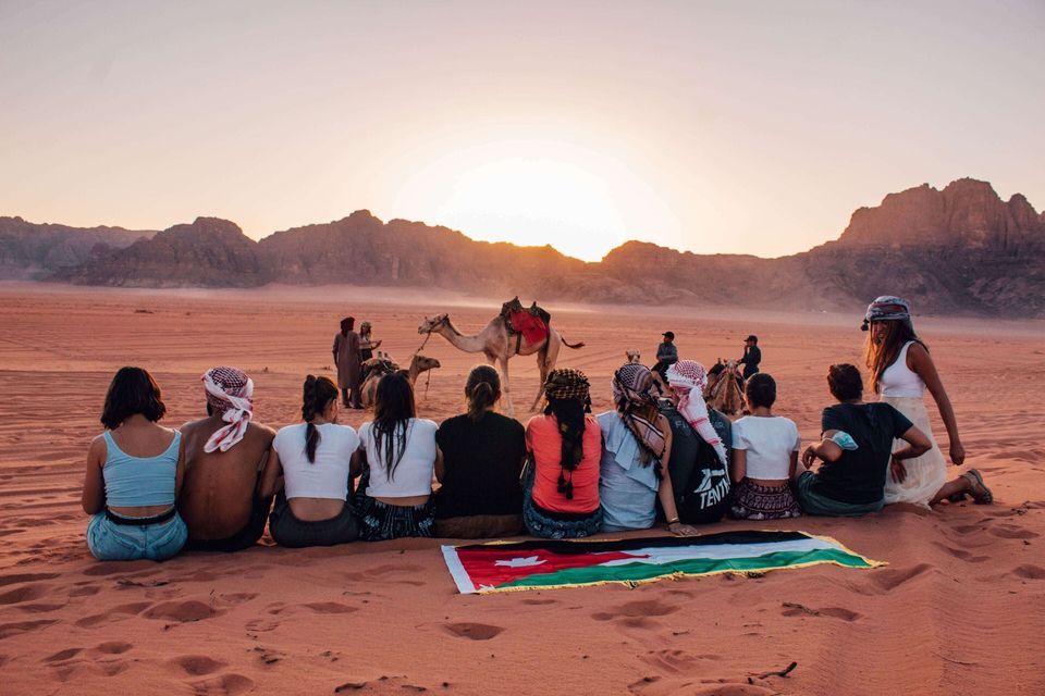 Foto di persone sedute nel deserto di Wadi Rum durante il tramonto in Giordania