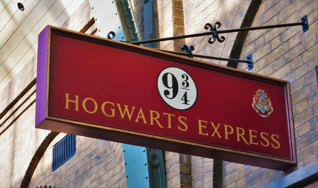 Ein rotes Hogwarts Express Schild mit der Nummer 9 3/4 hängt an einer Ziegelwand.