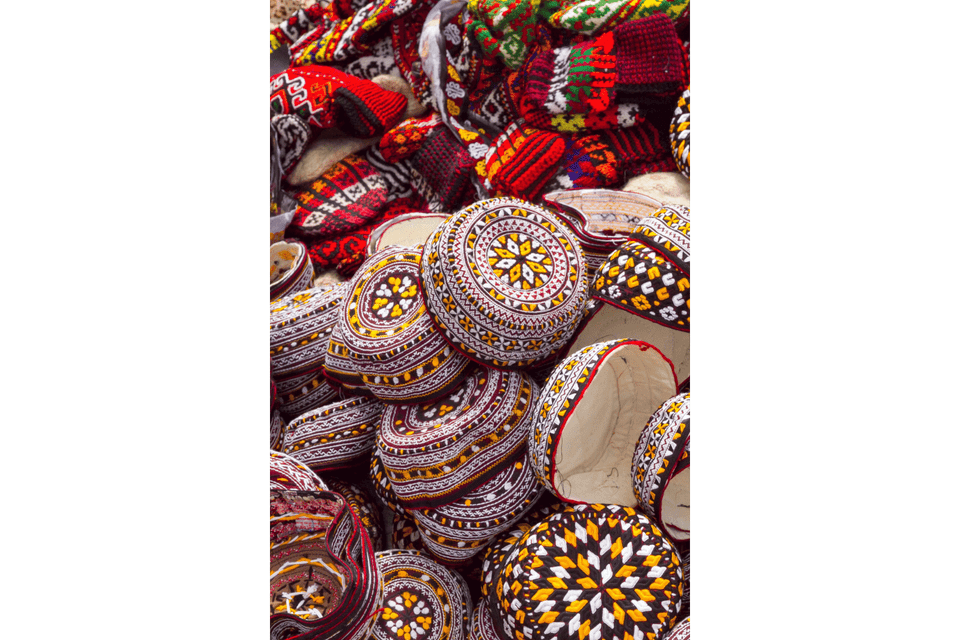 Un grande mucchio di colorati zuccotti e berretti di lana tradizionalmente ricamati con vari motivi geometrici.