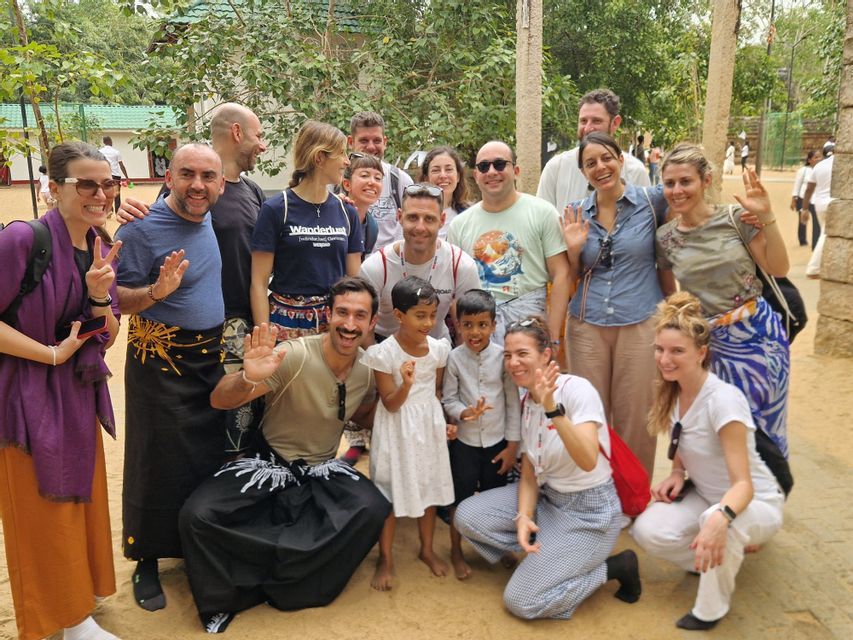Eine WeRoad-Gruppe auf Reisen posiert für ein Foto mit zwei lächelnden, winkenden Kindern aus der Region im Freien.