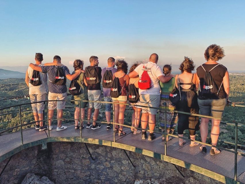 Un groupe WeRoad en voyage réuni sur un point de vue, admirant un paysage verdoyant et vallonné au coucher du soleil.