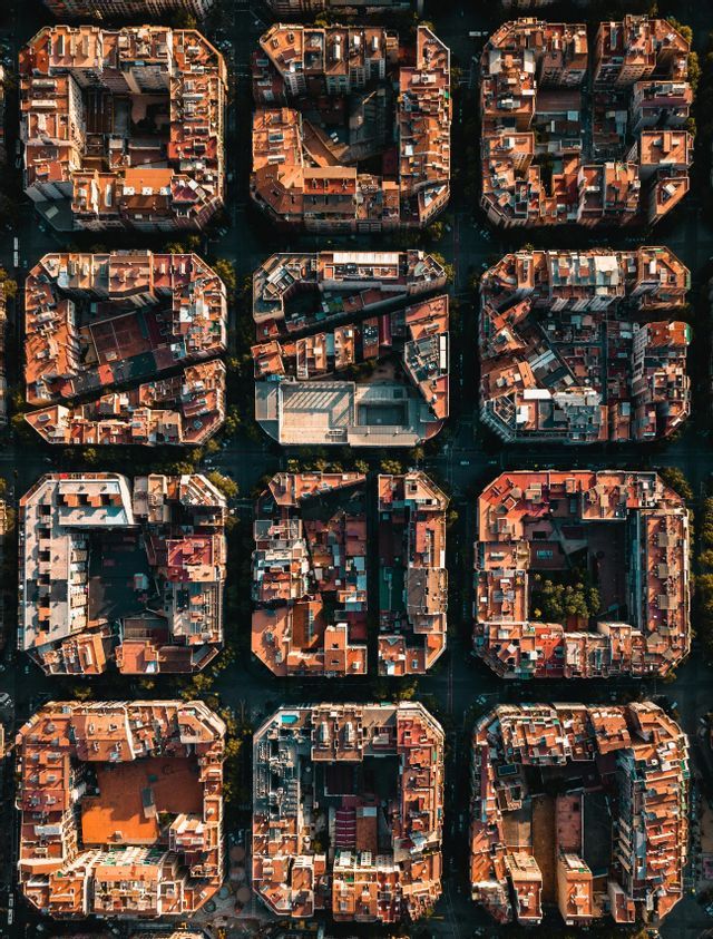 Vista aerea dall'alto di isolati urbani con tetti in terracotta, disposti a griglia uniforme.