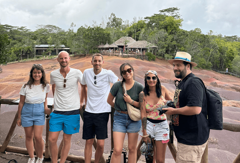 Un voyage de groupe WeRoad de six personnes souriant pour une photo devant un paysage avec une terre ondulée colorée et une forêt luxuriante.