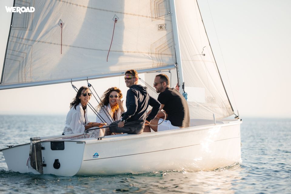 Quattro persone di un gruppo WeRoad sorridono e ridono navigando su una piccola barca.