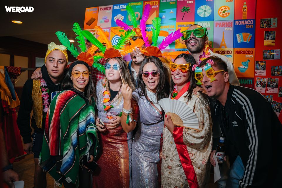 Un viaggio di gruppo WeRoad in posa per una foto con costumi colorati, occhiali oversize e copricapi davanti a uno sfondo a tema.