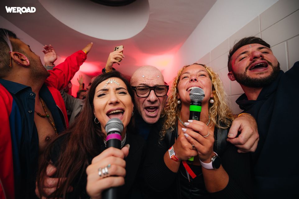 Un viaggio di gruppo WeRoad con persone che cantano e ridono ai microfoni durante una festa karaoke.