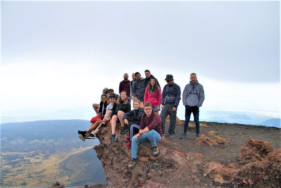 Un voyage de groupe WeRoad posant ensemble sur un affleurement rocheux et volcanique dominant un vaste paysage sous un ciel nuageux.