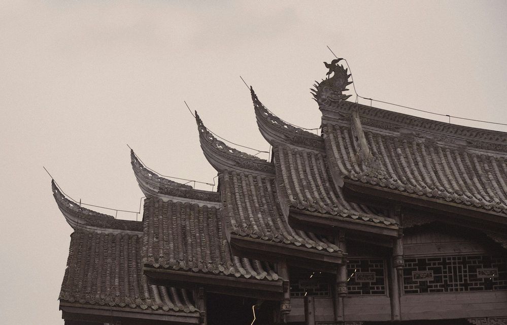 Una fotografia in bianco e nero che mostra i tetti a tegole stratificati e decorati di un tradizionale edificio dell'Asia orientale.