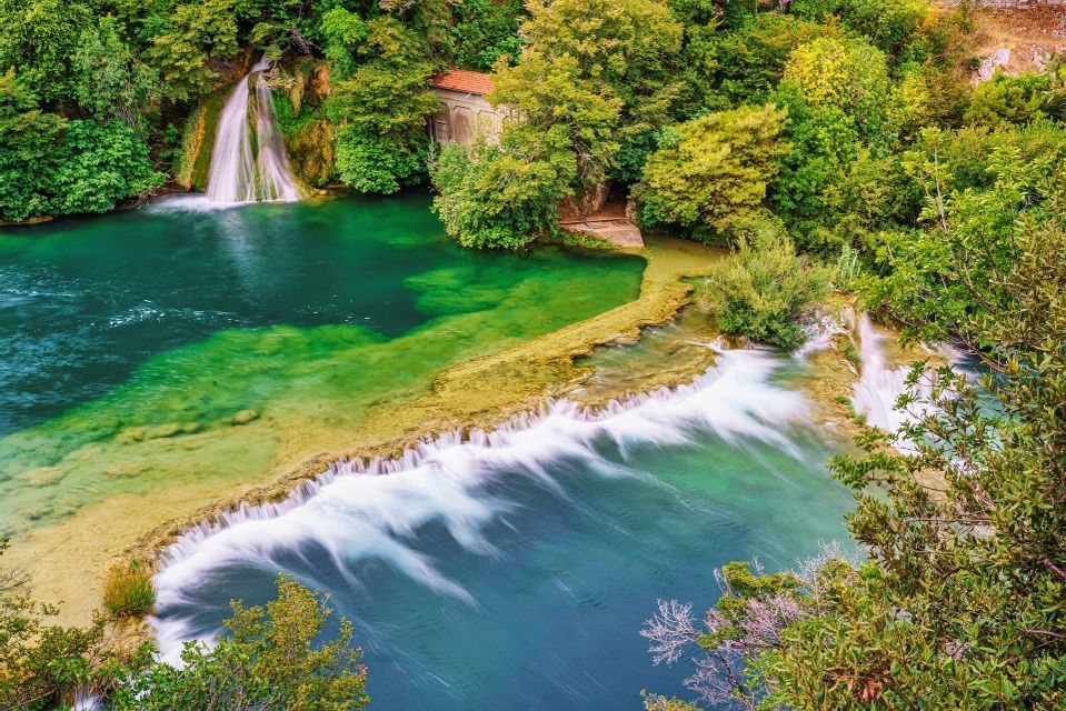Una vista aerea di cascate che scorrono su terrazze in un fiume turchese e blu, circondato da lussureggianti alberi verdi.