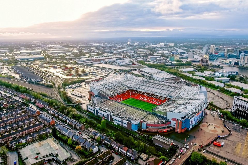 Una veduta aerea di Old Trafford, lo stadio del Manchester United, circondato dalla città circostante sotto un cielo nuvoloso.