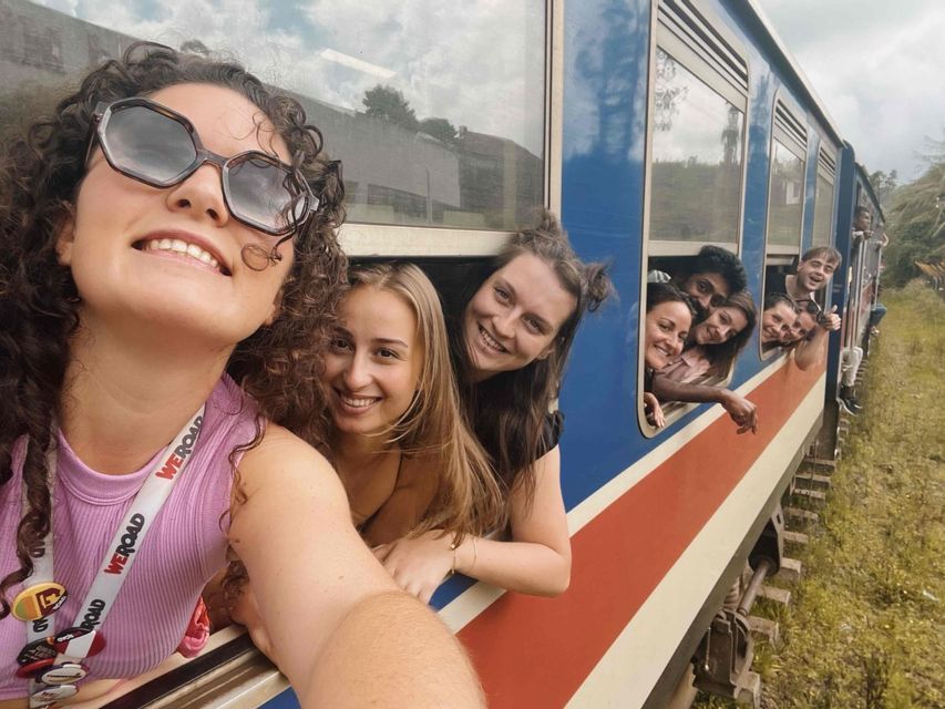 Un groupe WeRoad sourit pour un selfie en se penchant par les fenêtres d'un train en marche.