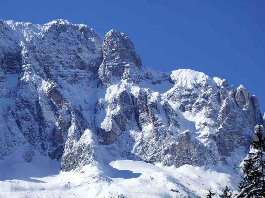 Le aspre cime rocciose delle montagne sono ricoperte da uno spesso strato di neve sotto un limpido cielo azzurro.