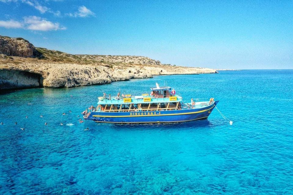 Voyage en groupe WeRoad sur un bateau ancré dans une eau turquoise, avec des nageurs près d'une côte rocheuse.