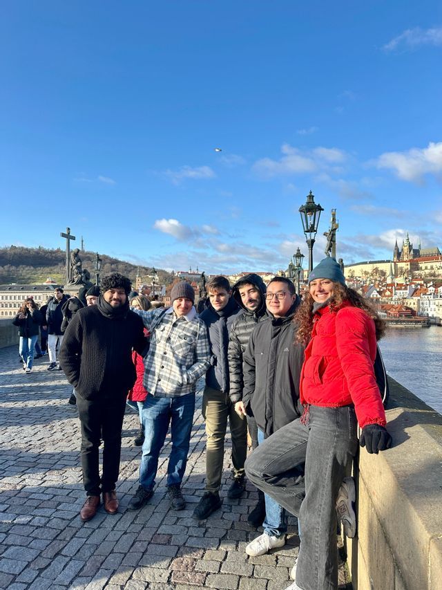 Un voyage de groupe WeRoad de six personnes souriantes pour une photo sur un pont pavé avec une ville historique en arrière-plan.
