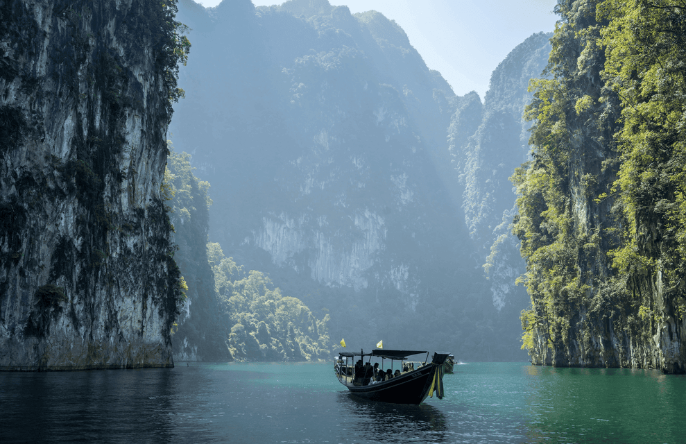 Un viaggio di gruppo WeRoad su una long-tail boat galleggia su acque calme tra imponenti scogliere calcaree coperte da una vegetazione lussureggiante.