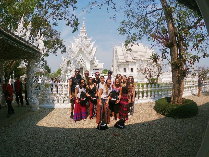 Un grupo de WeRoad posando para una foto frente a un templo blanco ornamentado bajo un cielo azul claro.