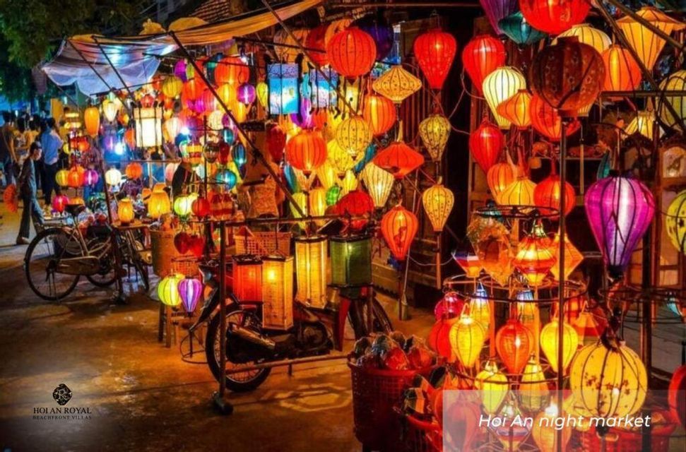 A night market stall filled with dozens of colorful, glowing lanterns of various shapes, with a bicycle parked in front.