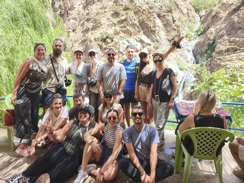 Un grupo de WeRoad posa para una foto en un cañón rocoso y exuberante con una pequeña cascada de fondo.