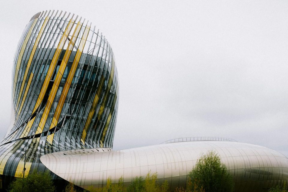 Un edificio moderno y curvo con paneles en espiral amarillos y de vidrio junto a una estructura baja y blanca bajo un cielo nublado.