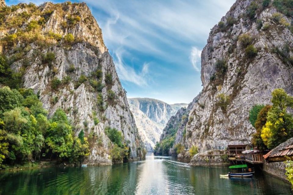 Ein Fluss fließt durch eine tiefe, felsige Schlucht mit bewaldeten Klippen unter einem blauen Himmel mit vereinzelten Wolken.