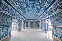 L'interno di una sala ornata con intricati motivi blu e bianchi che coprono le pareti, gli archi e il soffitto.