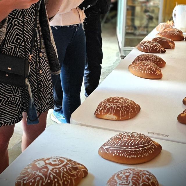 Eine WeRoad-Gruppe steht an einem Tisch mit mehreren runden Broten, die aufwendig mit weißer Zuckerglasur verziert sind.
