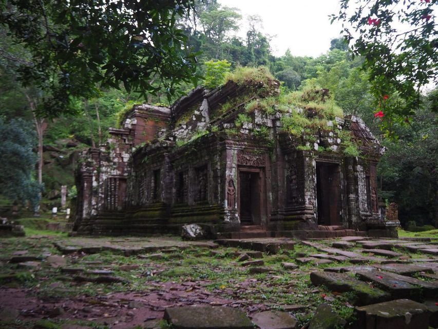 Un'antica rovina di tempio in pietra, ricoperta di muschio e vegetazione, nascosta in una fitta foresta verde.